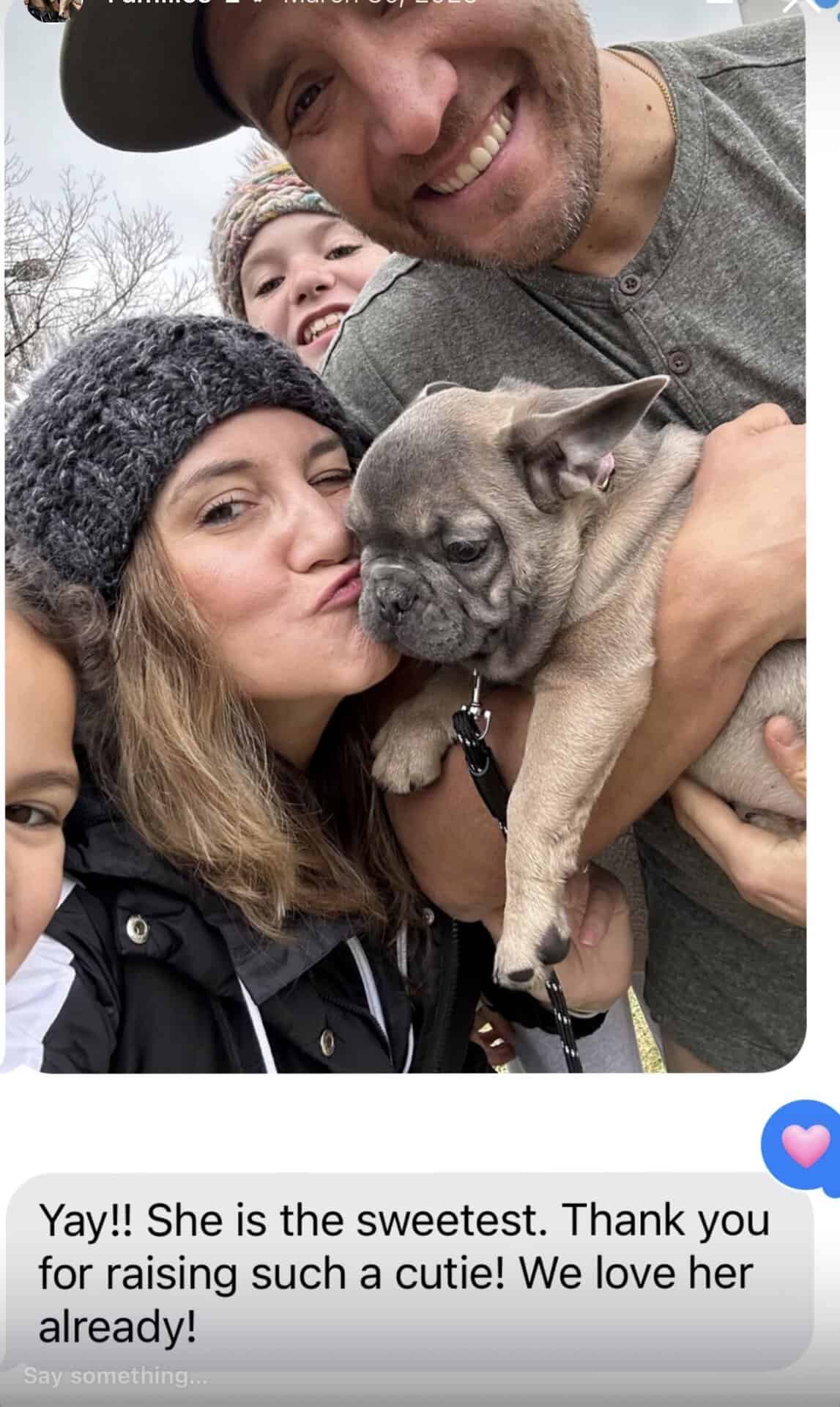 Family selfie with mom kissing their new Frenchie puppy